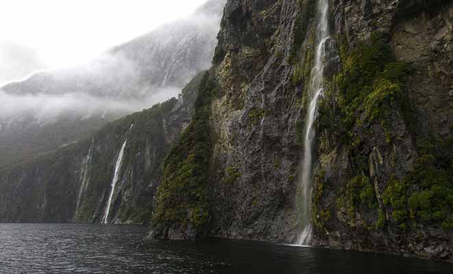 Lorsque la pluie cesse et qu'une éclaircie révèle le paysage, on découvre des centaines de cascades qui se déversent dans les eaux sombres du fiord.