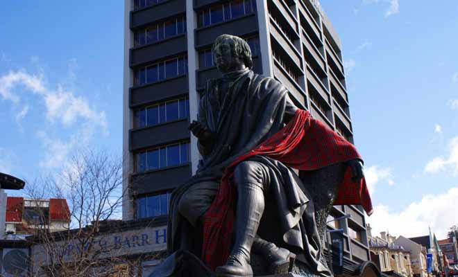 Robert Burns est un poète écossais dont la statue orne la place de l'Octagon. La légende veut qu'il tourne le dos à l'Église anglicane pour surveiller le pub de l'Oban Hotel. Si le pub a disparu, la statue est restée.