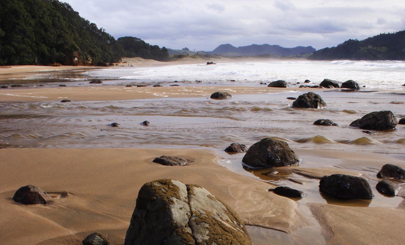 La source remonte à la surface à partir d'une faille située près des rochers de la plage.
