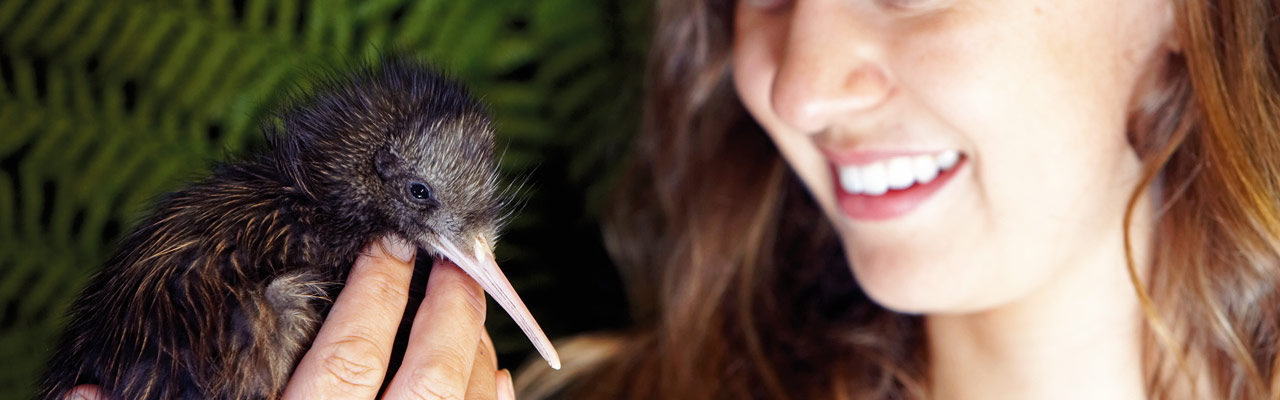 Young woman holding a kiwi in her hand.