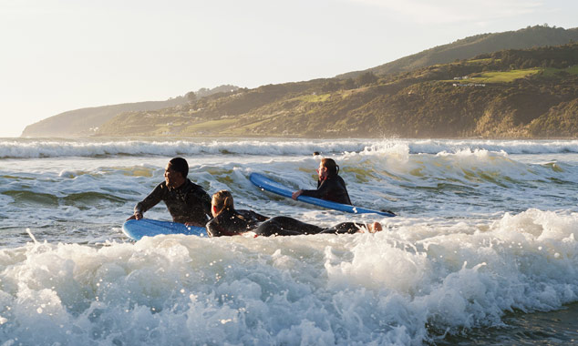 Jonge mensen nemen een surf les.